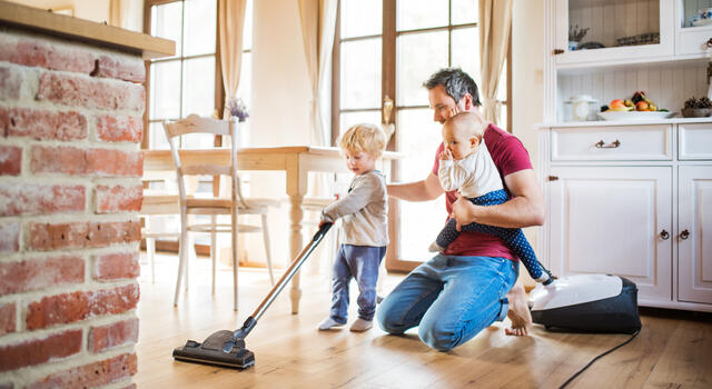 papa stofzuigt met een peuter en een baby