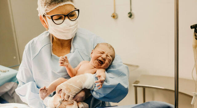 zorgprofessional houdt een pasgeboren baby vast