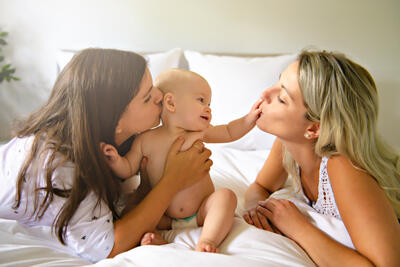 2 mama's met een baby spelen op het bed